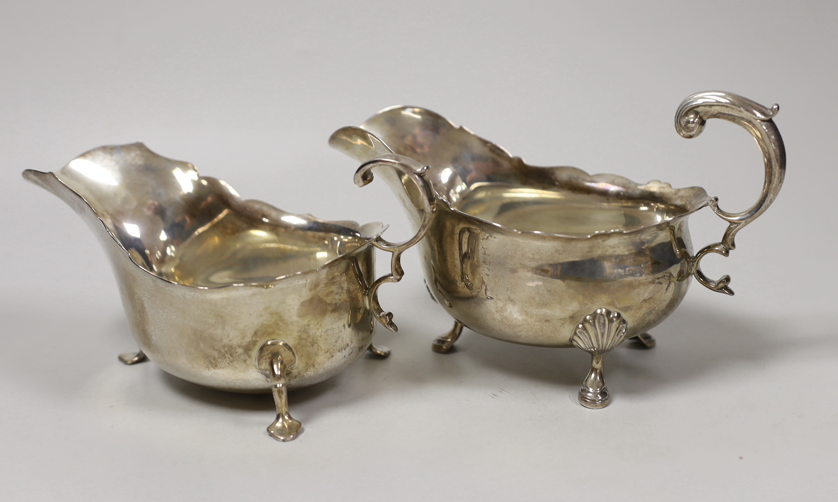 Two early 20th century silver sauceboats, with flying scroll handles, London, 1911 and Sheffield, 1907, 15.2oz.